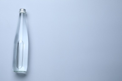 Glass bottle with water on white background, top view. Space for text