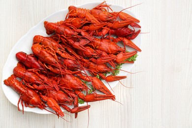Photo of Plate with delicious red boiled crayfish on white wooden table, top view