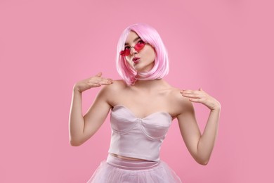 Photo of Pink look. Beautiful girl in wig and clothes wearing bright sunglasses on color background