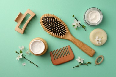 Photo of Flat lay composition with wooden hairbrush, comb and cosmetic products on turquoise background