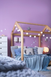 Photo of Child's room interior with comfortable bed and garland