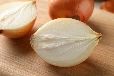 Photo of Whole and cut onions on wooden board, closeup