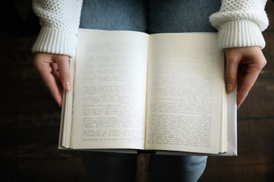 Photo of Young woman reading book indoors, top view