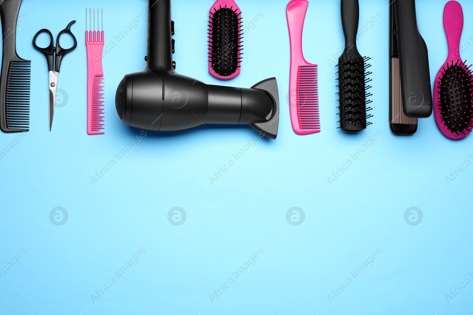 Photo of Flat lay composition of professional hairdresser tools on light blue background, space for text