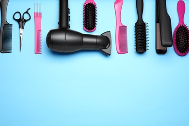 Flat lay composition of professional hairdresser tools on light blue background, space for text