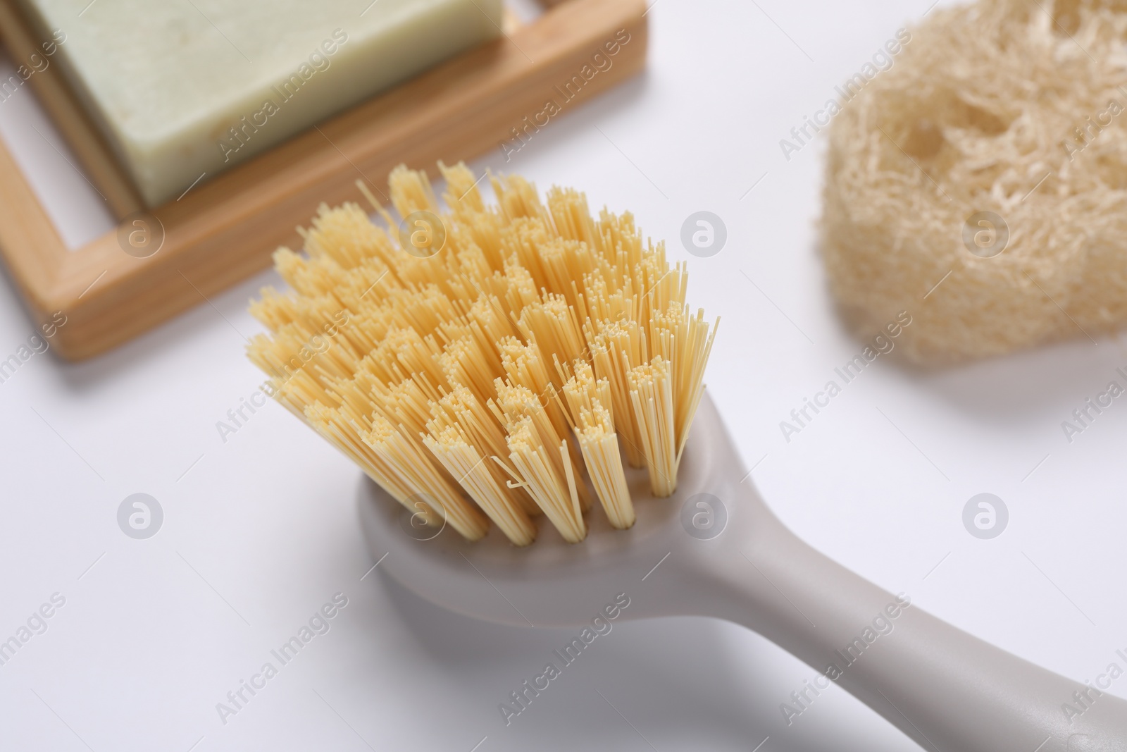 Photo of Cleaning brush, soap bar and loofah on white background, closeup