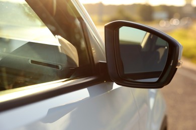 Photo of Side view mirror of modern car outdoors on sunny day, closeup