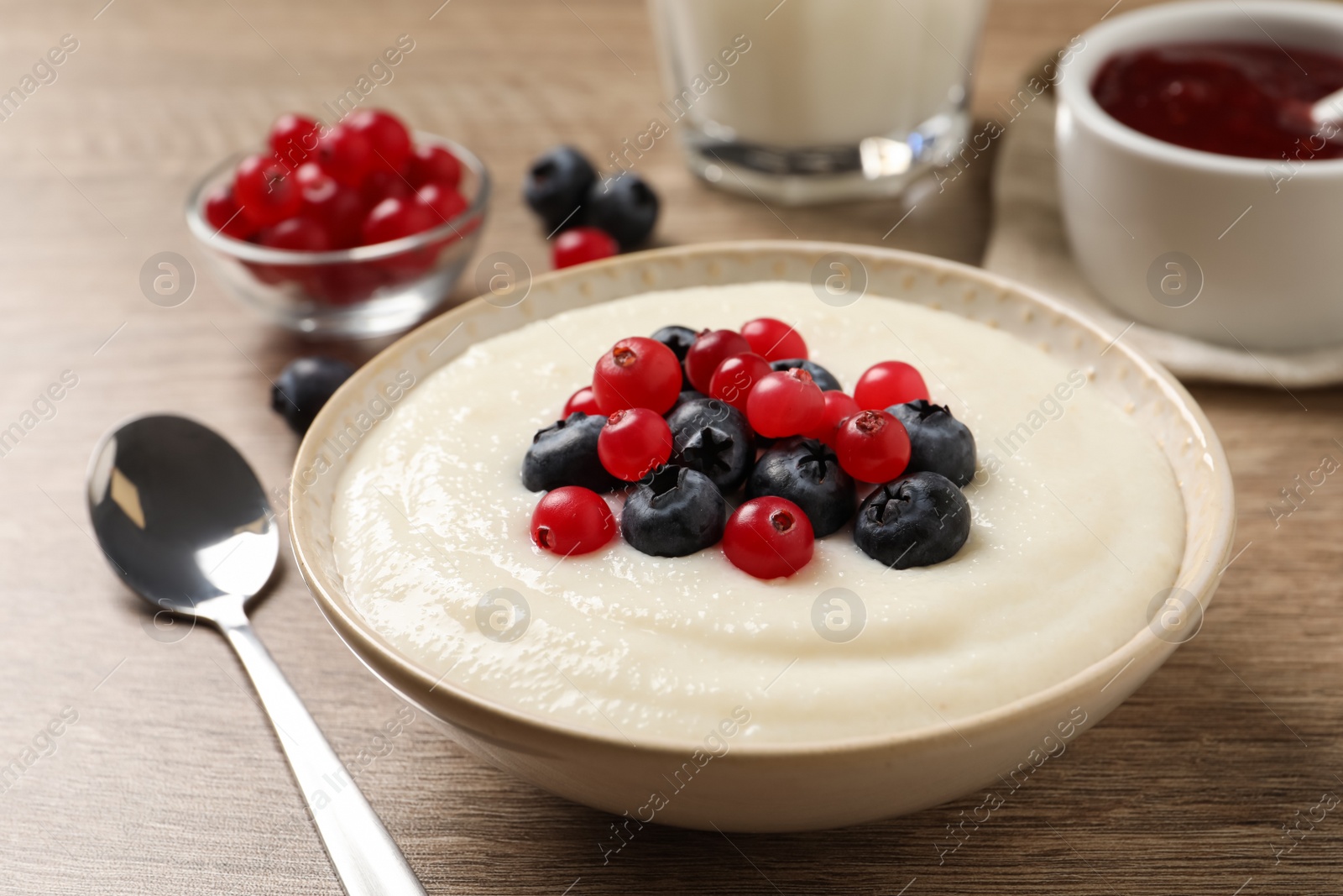 Photo of Delicious semolina pudding with berries on wooden table