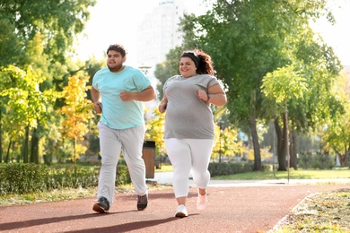Photo of Overweight couple running together in park on sunny day