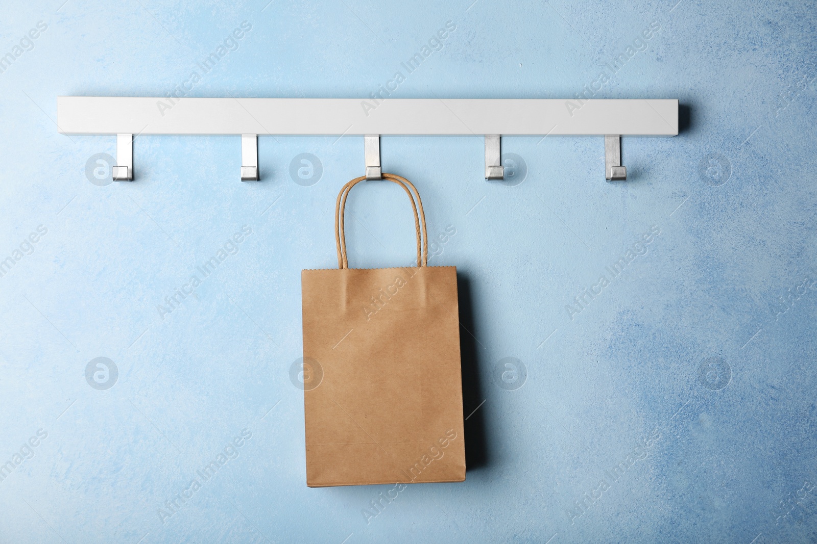 Photo of Rack with paper shopping bag on color wall