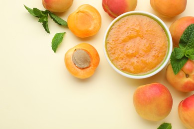Photo of Apricot puree in bowl and fresh fruits on beige background, flat lay. Space for text