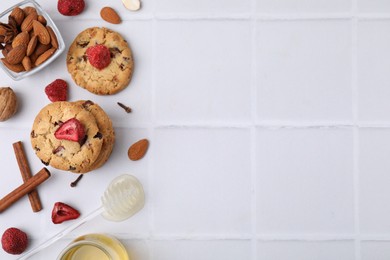 Photo of Cookies with freeze dried fruits, cinnamon, honey and nuts on white tiled table, flat lay. Space for text