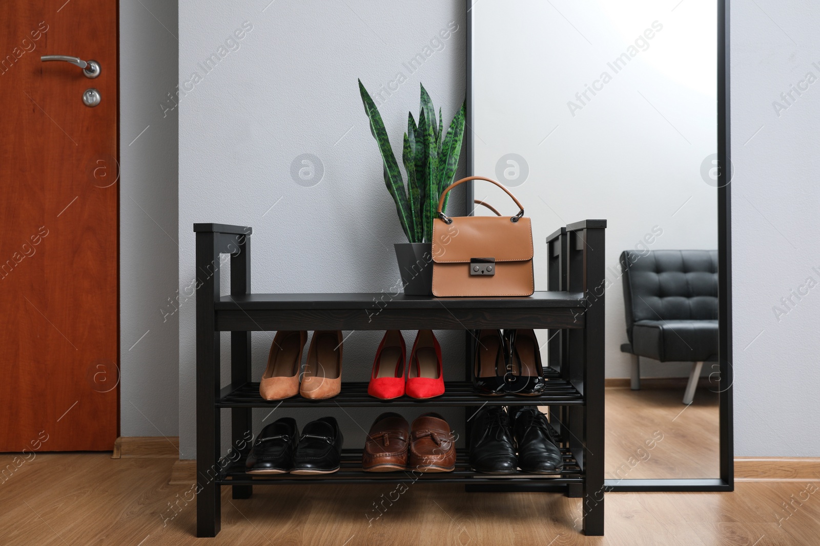 Photo of Shelving unit with stylish shoes and large mirror near grey wall in hallway