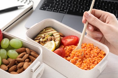 Woman eating healthy products high in vegetable fats near laptop at wooden table, closeup