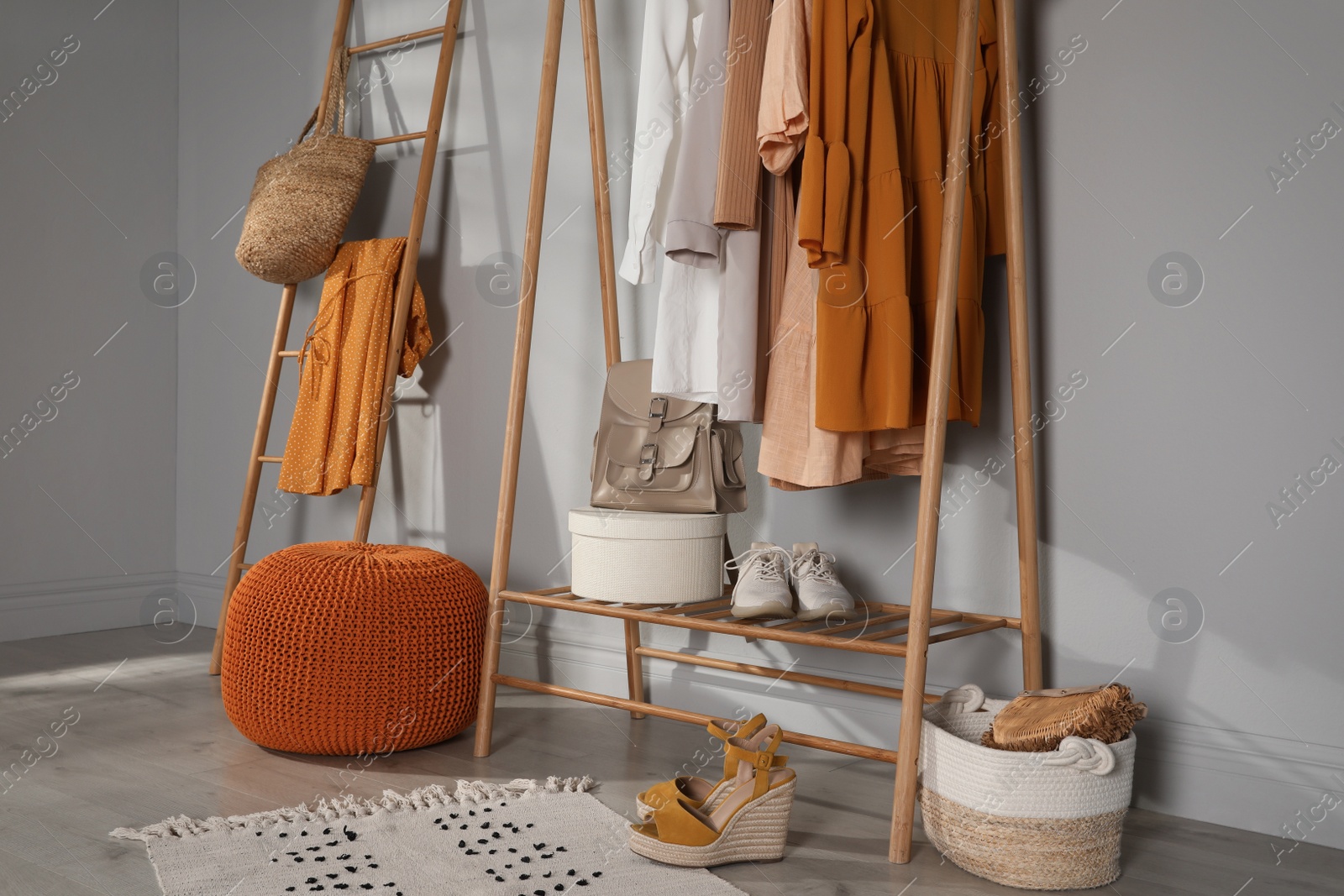 Photo of Modern dressing room interior with stylish clothes, shoes and orange pouf