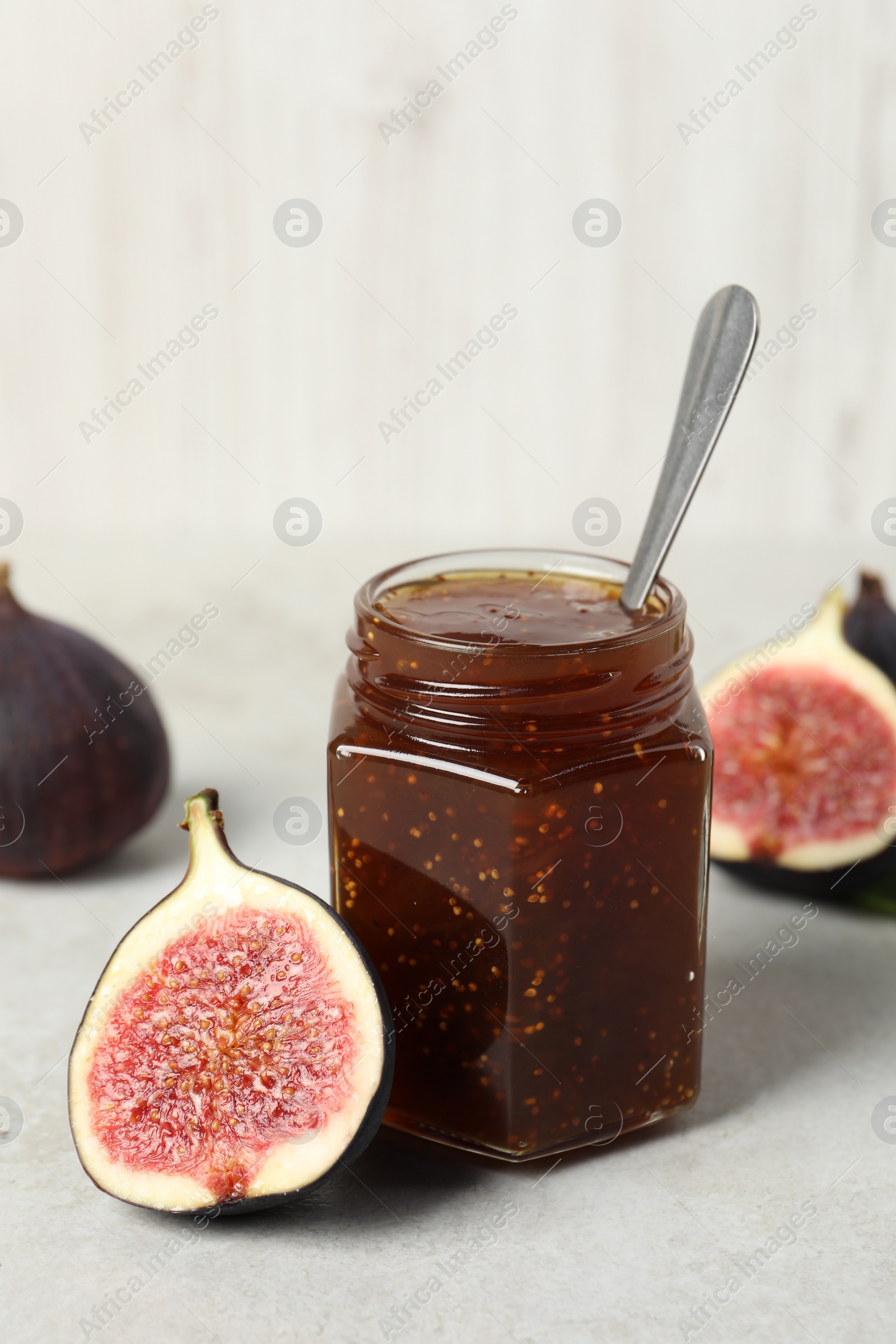 Photo of Glass jar with tasty sweet jam and fresh figs on white table