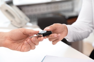 Photo of Salesman giving car key to customer in salon