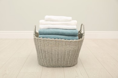 Photo of Wicker basket with folded towels on floor in room