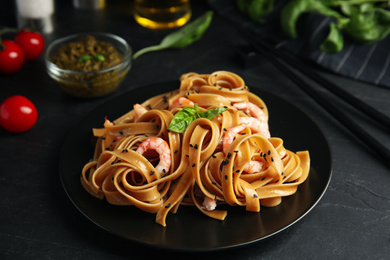 Photo of Tasty buckwheat noodles with shrimps served on black table