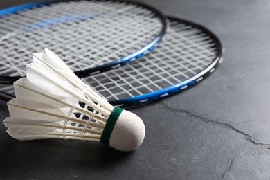 Photo of Feather badminton shuttlecock and rackets on grey textured table, closeup