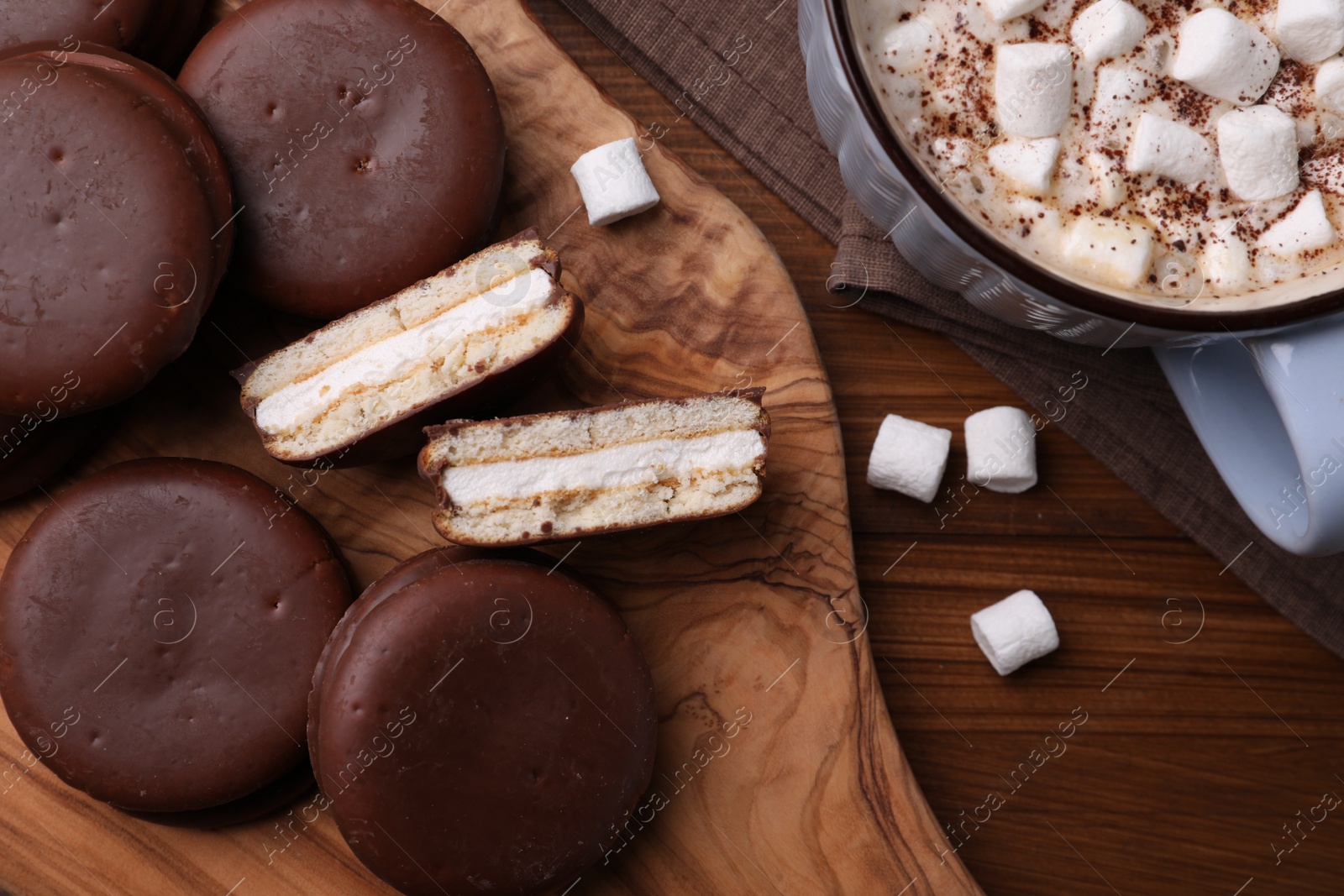 Photo of Tasty choco pies and cocoa with marshmallows on wooden table, flat lay