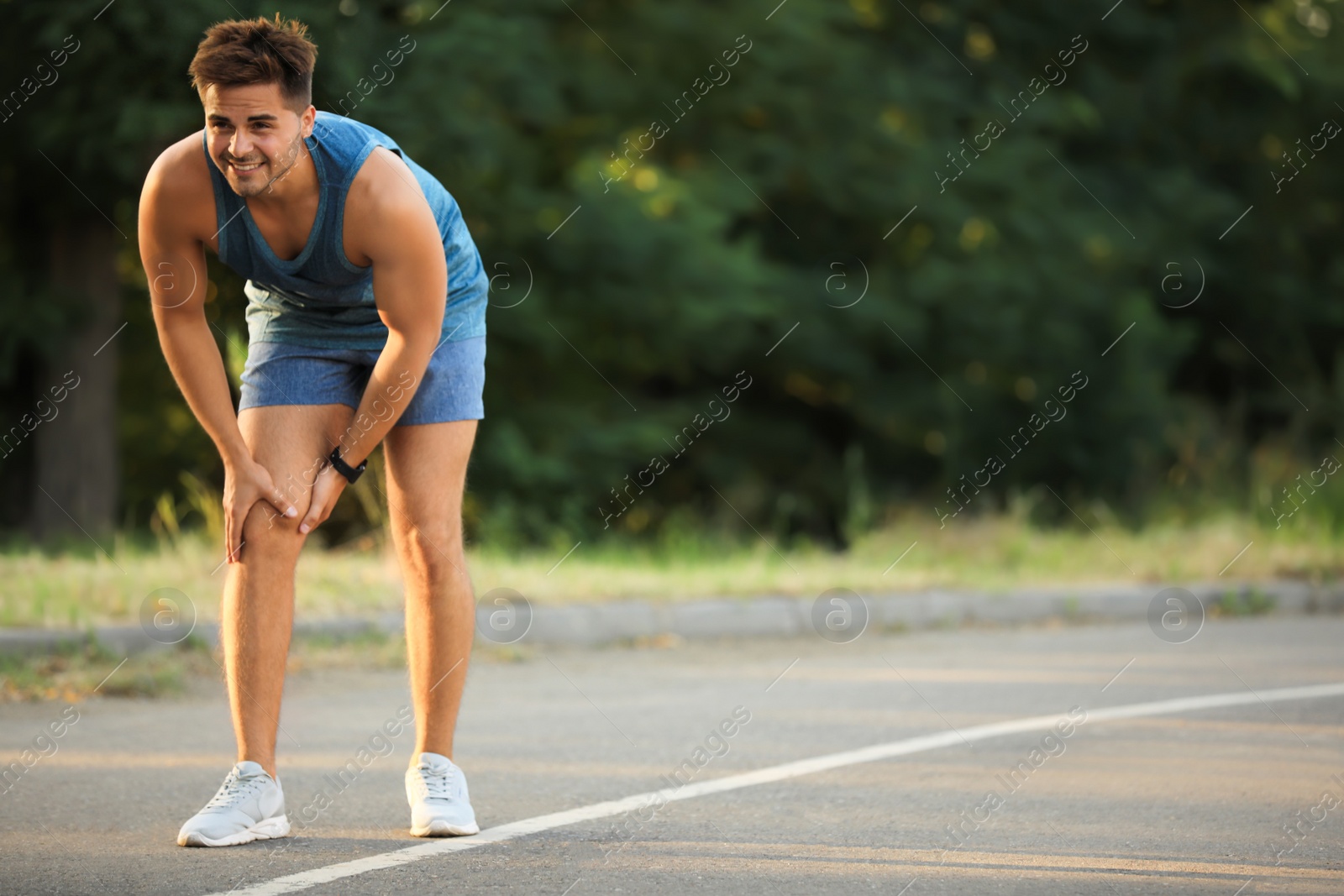 Photo of Young man in sportswear having knee problems in park