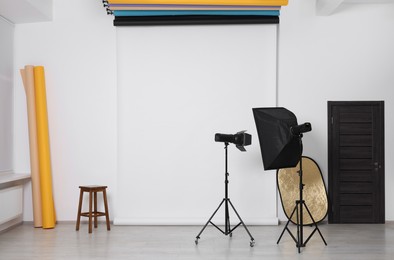 Photo of Different photo backgrounds, stool and professional lighting equipment in studio
