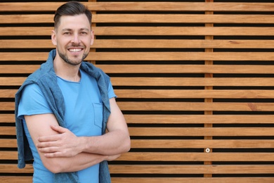 Portrait of young man in stylish outfit near wooden wall