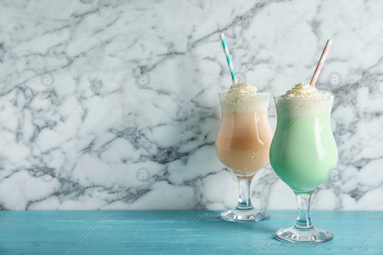 Photo of Glasses with delicious milk shakes on table against marble background. Space for text