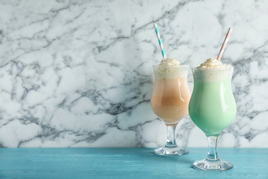 Photo of Glasses with delicious milk shakes on table against marble background. Space for text