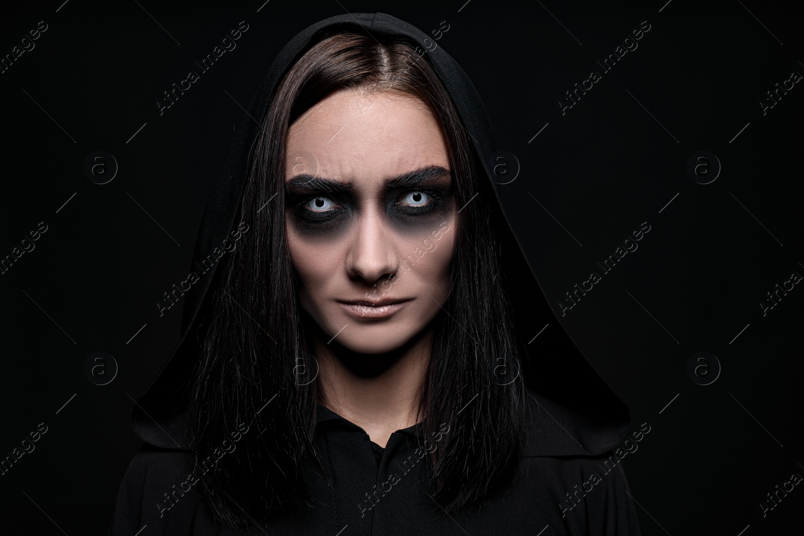 Photo of Mysterious witch with spooky eyes on black background