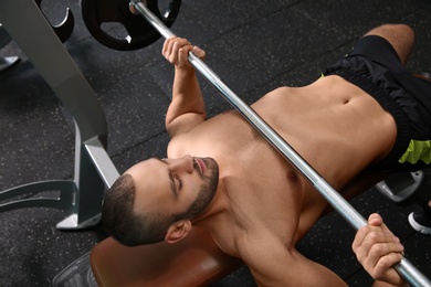 Photo of Strong young man lifting barbell in gym