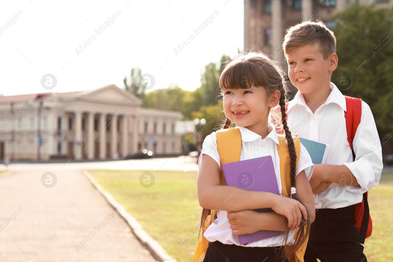 Photo of Little kids with backpacks and notebooks outdoors. Stationery for school