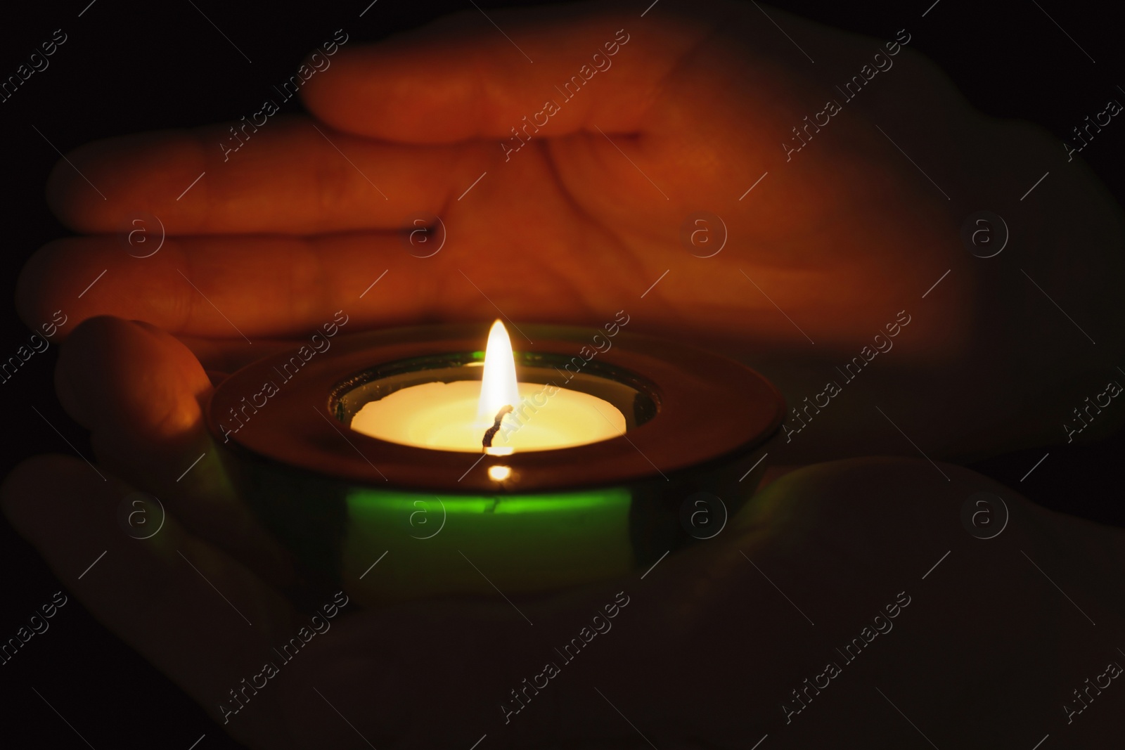 Photo of Young person holding burning candle in darkness, closeup