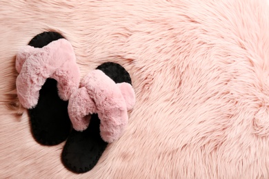 Photo of Pair of soft slippers on pink faux fur, flat lay. Space for text
