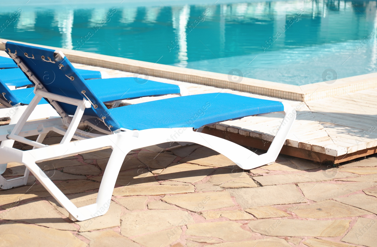 Photo of Comfortable loungers at clean swimming pool on sunny day