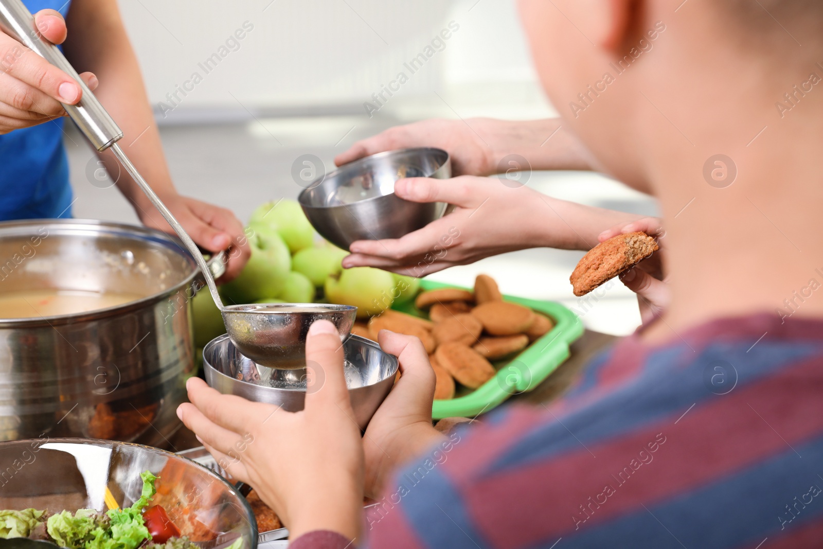 Photo of Poor little children receiving food from volunteer in charity centre, closeup