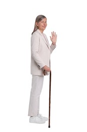 Senior woman with walking cane waving on white background