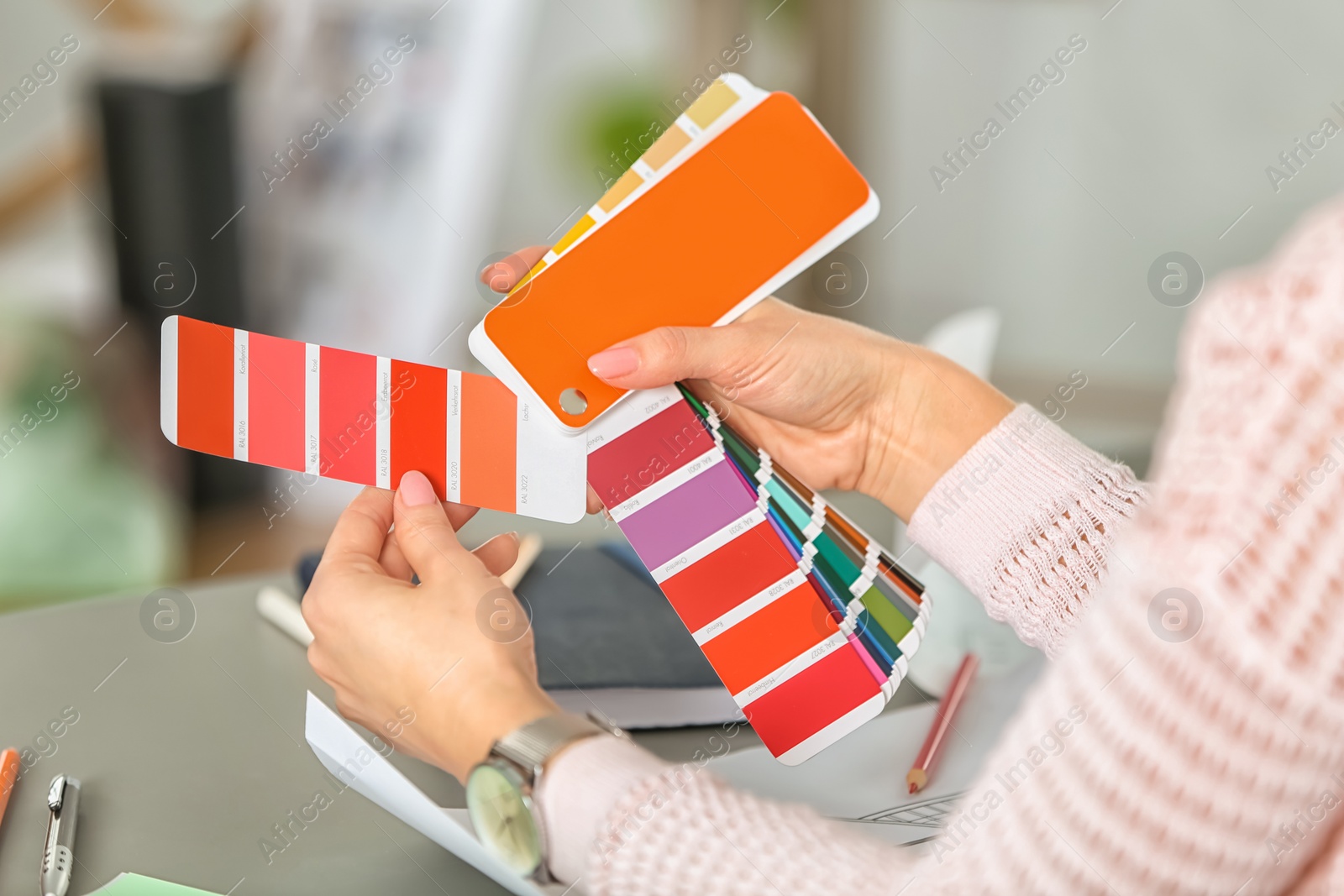 Photo of Female designer working with color palette samples at table