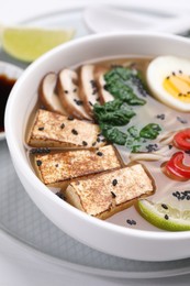 Photo of Delicious vegetarian ramen in bowl on white table, closeup
