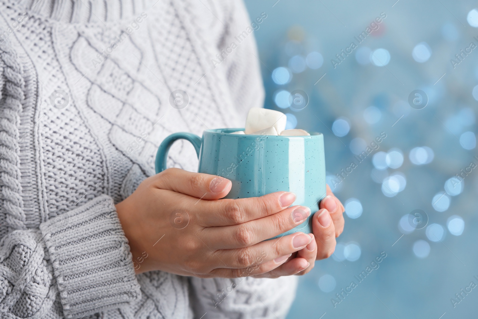 Photo of Young woman with delicious hot cocoa drink on blurred background, closeup