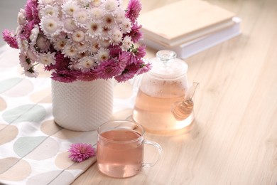 Photo of Fresh delicious herbal tea, books and beautiful bouquet on wooden table. Space for text