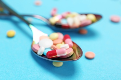 Spoons and different pills on color background