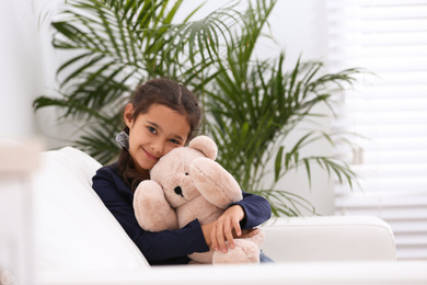 Portrait of cute little girl with toy bear in living room