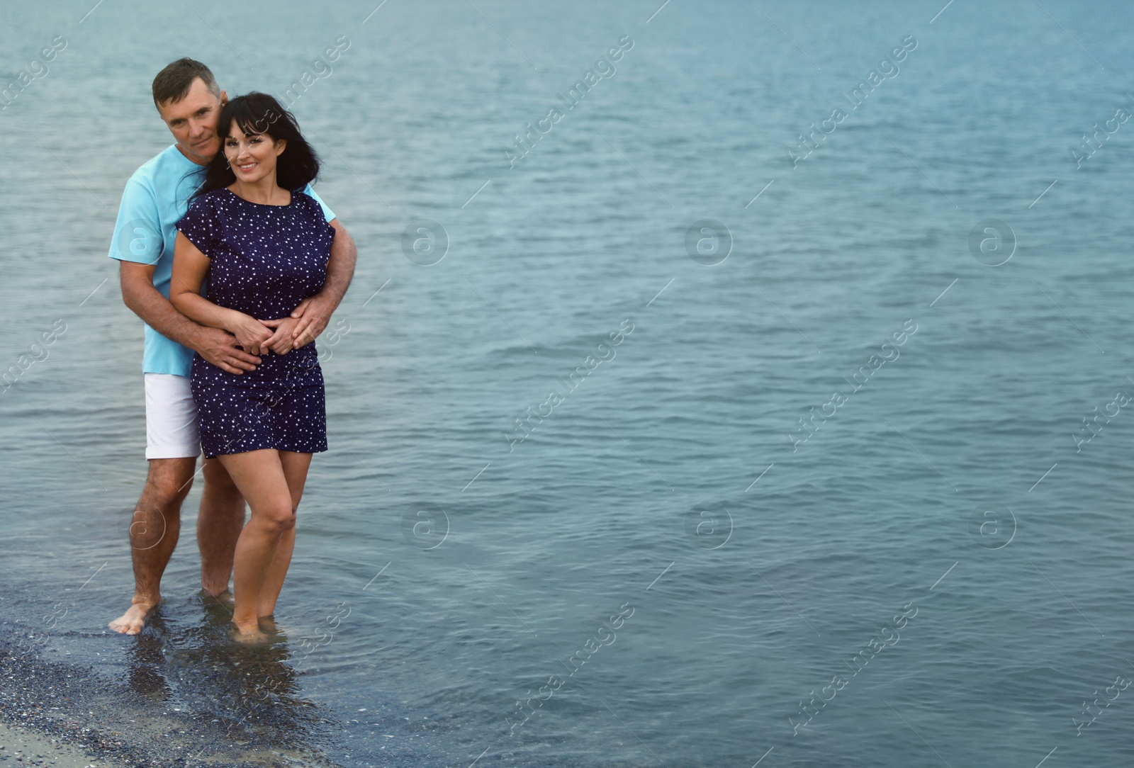 Photo of Happy mature couple spending time together on sea beach. Space for text