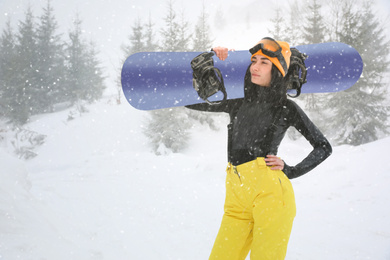 Young woman with snowboard wearing winter sport clothes outdoors