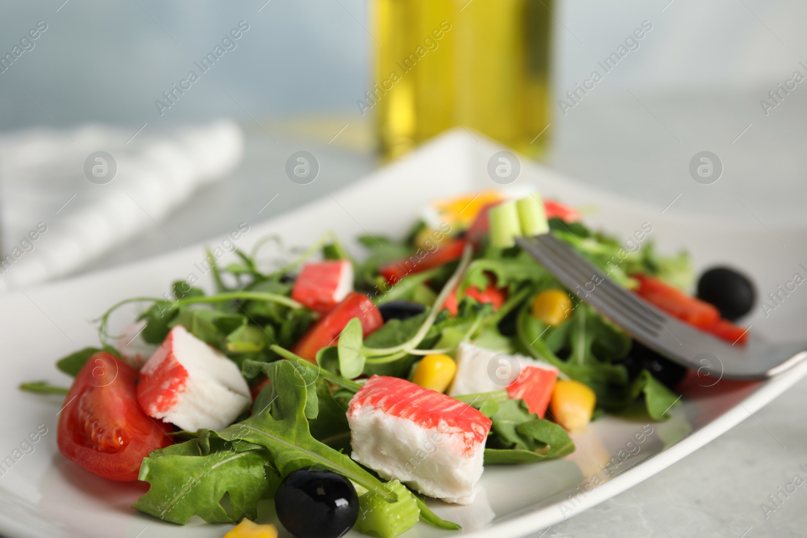 Photo of Tasty crab stick salad served on light grey table, closeup