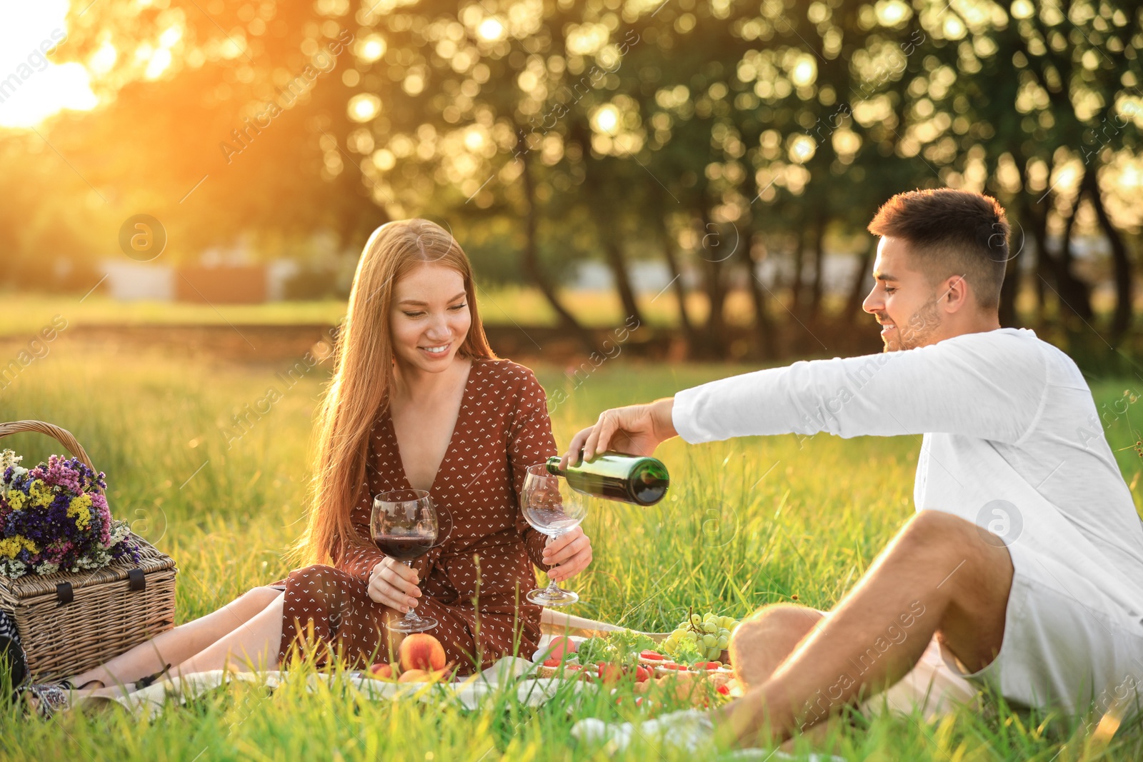 Photo of Young man and his girlfriend having picnic in green park