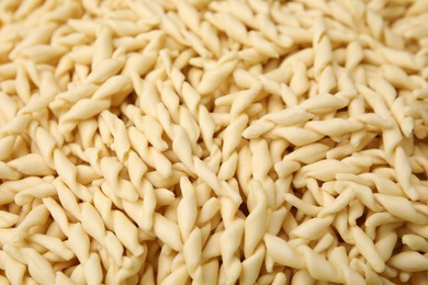 Uncooked trofie pasta as background, closeup view
