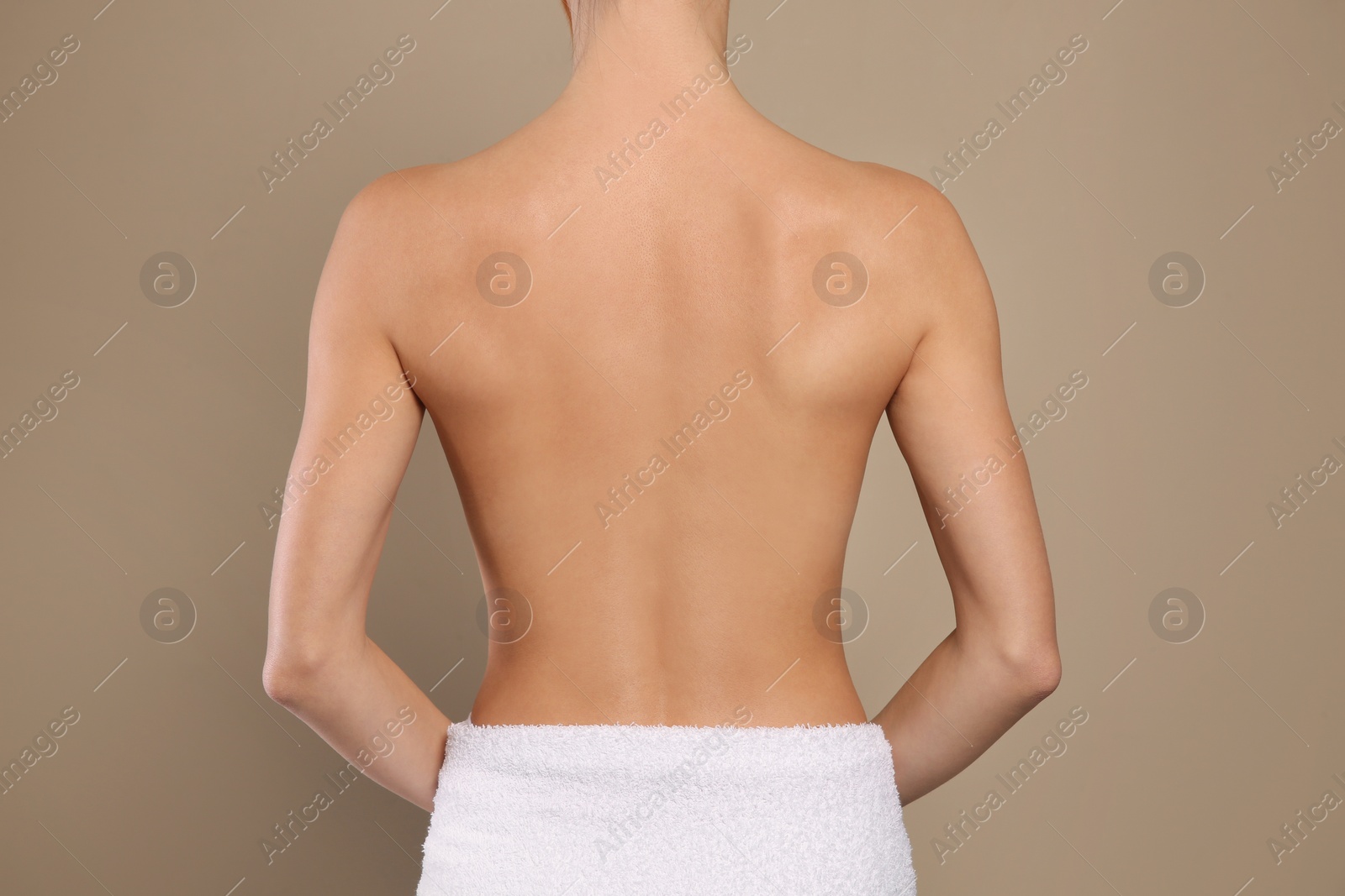 Photo of Back view of woman with perfect smooth skin on beige background, closeup. Beauty and body care